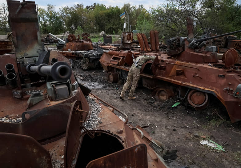 Военнослужащий проверяет сгоревший российский бронетранспортер в Изюме